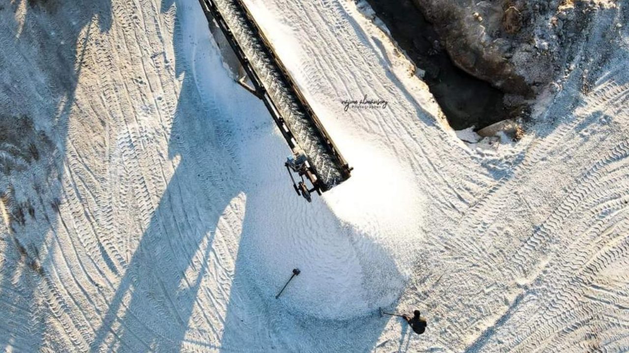 Harvested solar salt stacked by a conveyor at the Al Mozan works in Libya, with a worker levelling the pile